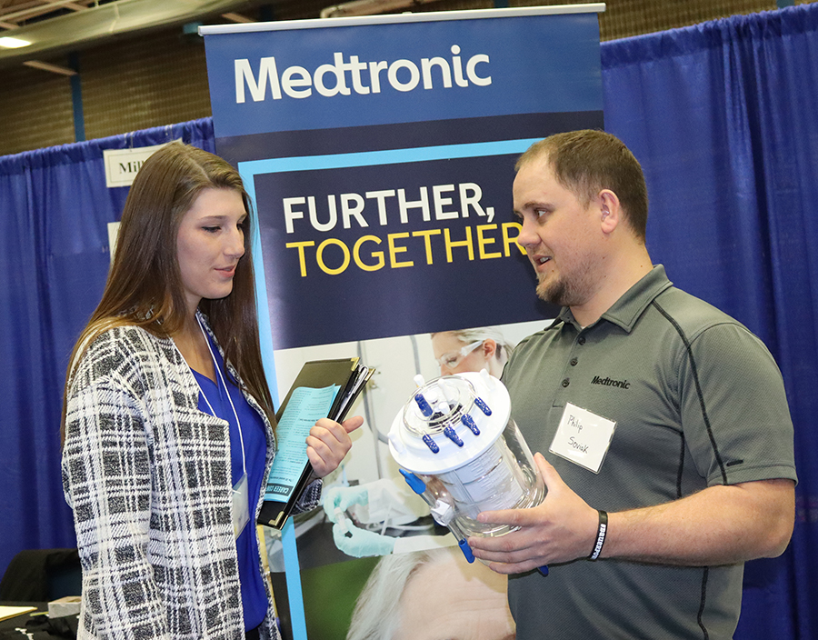 Philip Soviak, of Medtronic, at right, explains a medical device to UW-Stout student Rayna Figueroa during the Spring Career Conference