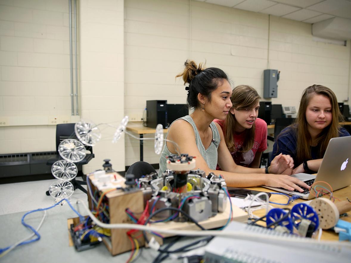 Robotics REU students Samantha Metevier, at left, Kayla Sneller and Emily Swanson work on a flexible robotic arm. The REU aims to improve the technology to enable robots that would allow the elderly and those with disabilities to keep living independently./UW-Stout photos by Brett T. Roseman