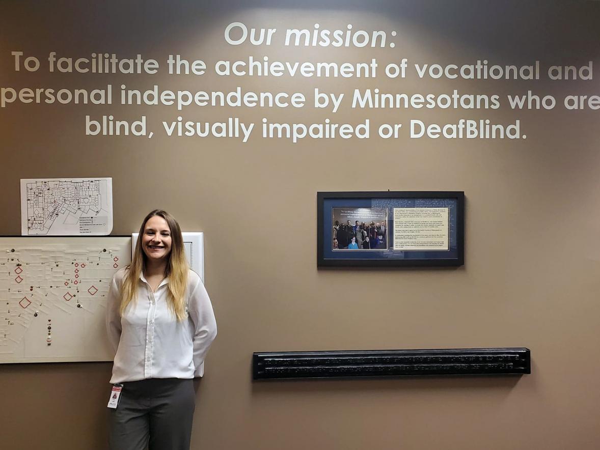 Alumna Natasha Jerde is director of Minnesota State Services for the Blind. She stands next to the agency's mission statement. 