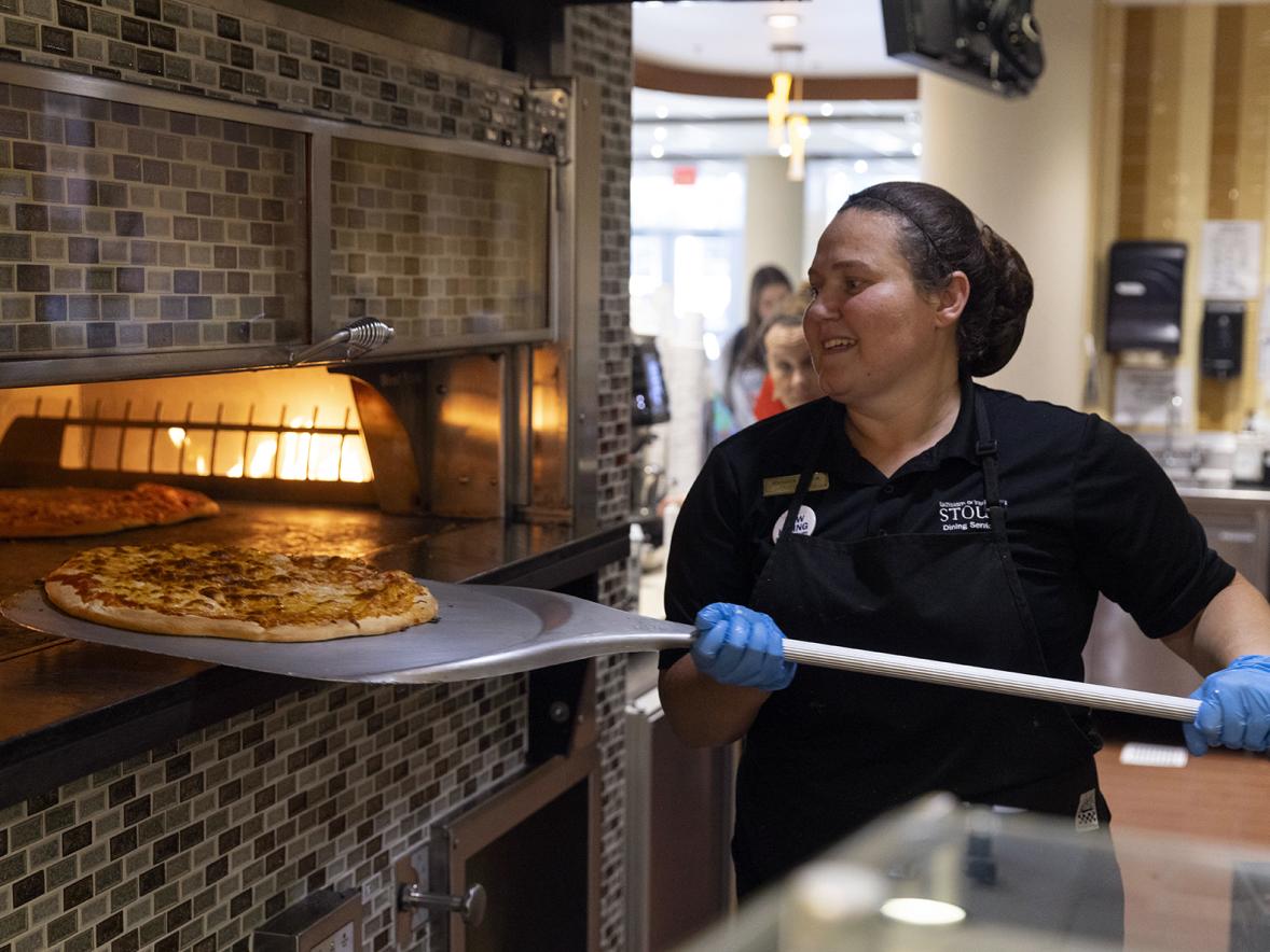 A Dining Services worker makes a pizza in the student center.